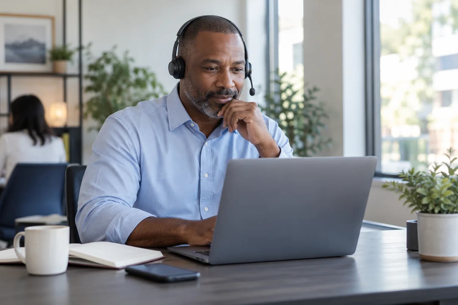 A customer support advisor listening to a caller at his workstation